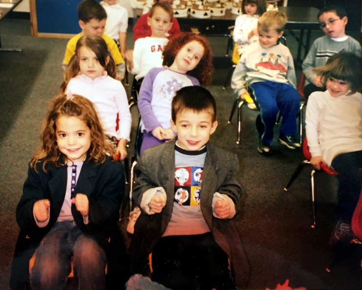Preschoolers in chairs set up like airplane rows, with two kids in jackets, serving as pilots